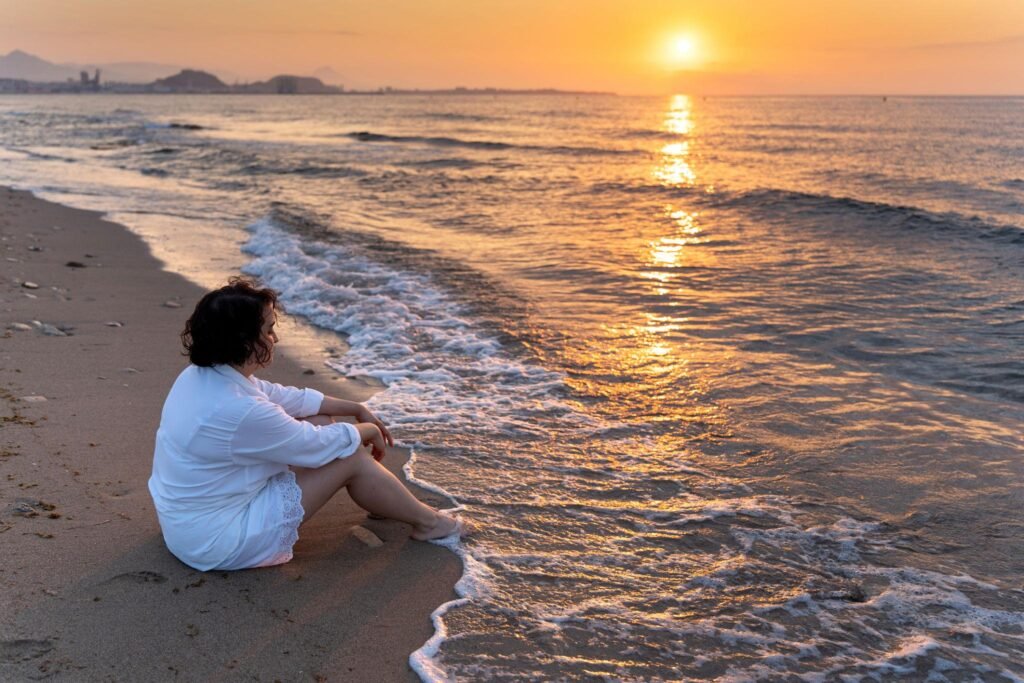 Woman meditating at sunrise on the beach