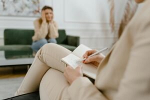 A therapist taking notes during a consultation with a patient, focusing on mental health.