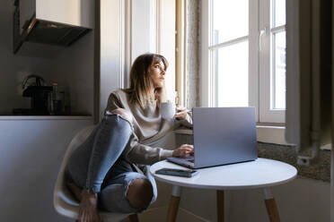 Woman sitting quietly by a window in soft natural light, reflecting on a difficult relationship and her own thoughts