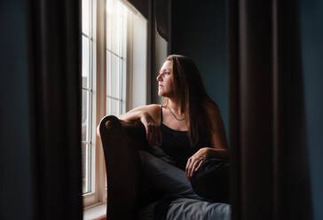 Woman reflecting quietly while reconsidering her role in helping someone with addiction.