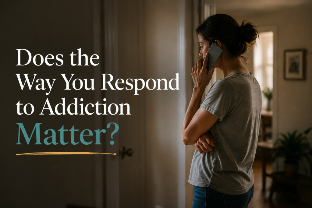 Woman standing in a hallway on the phone, pausing during a difficult conversation about a loved one’s addiction.